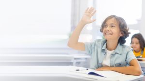 Anak laki-laki sedang mengangkat tangan pertanda kehadiran absensi